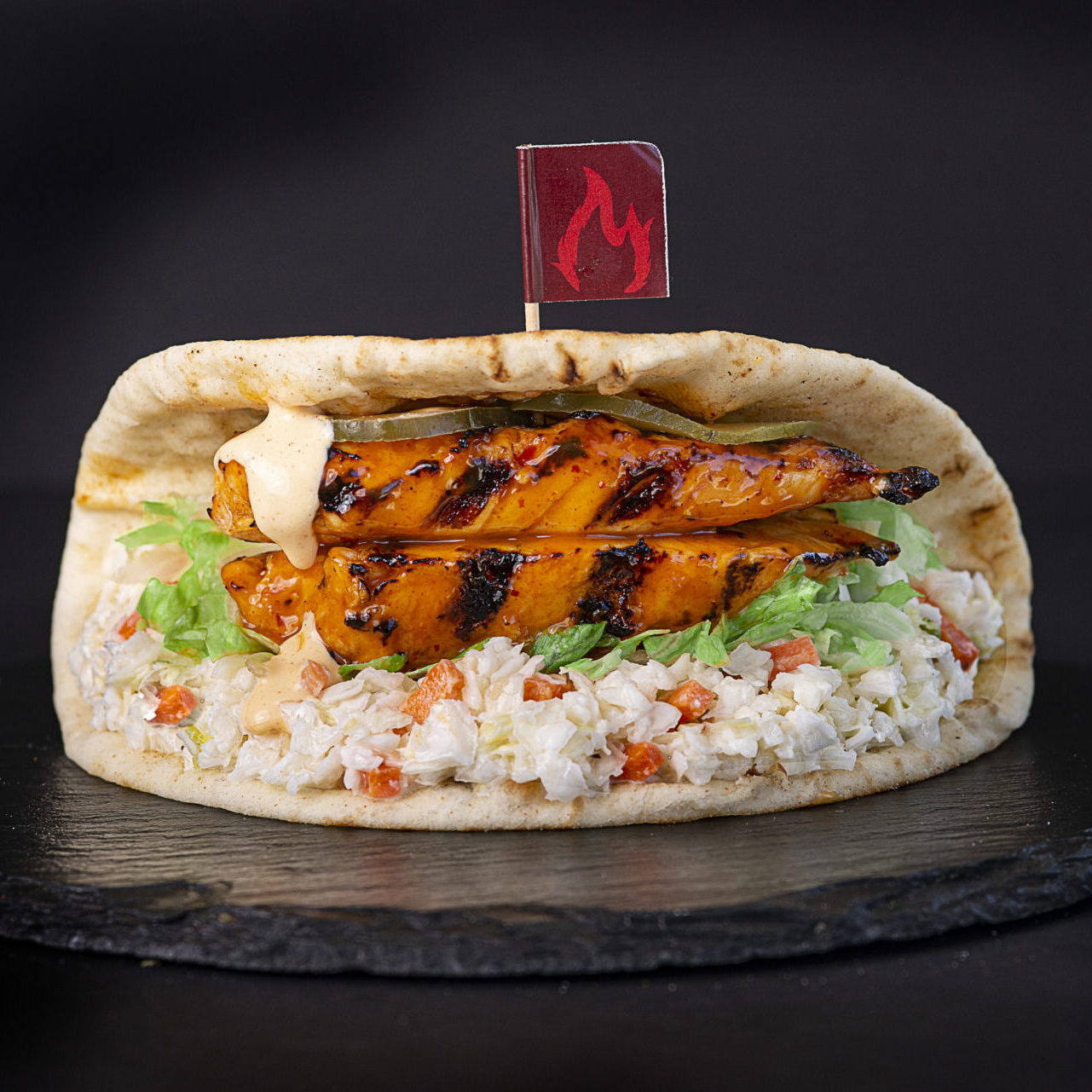 A pita sandwich with rice and chicken on top.