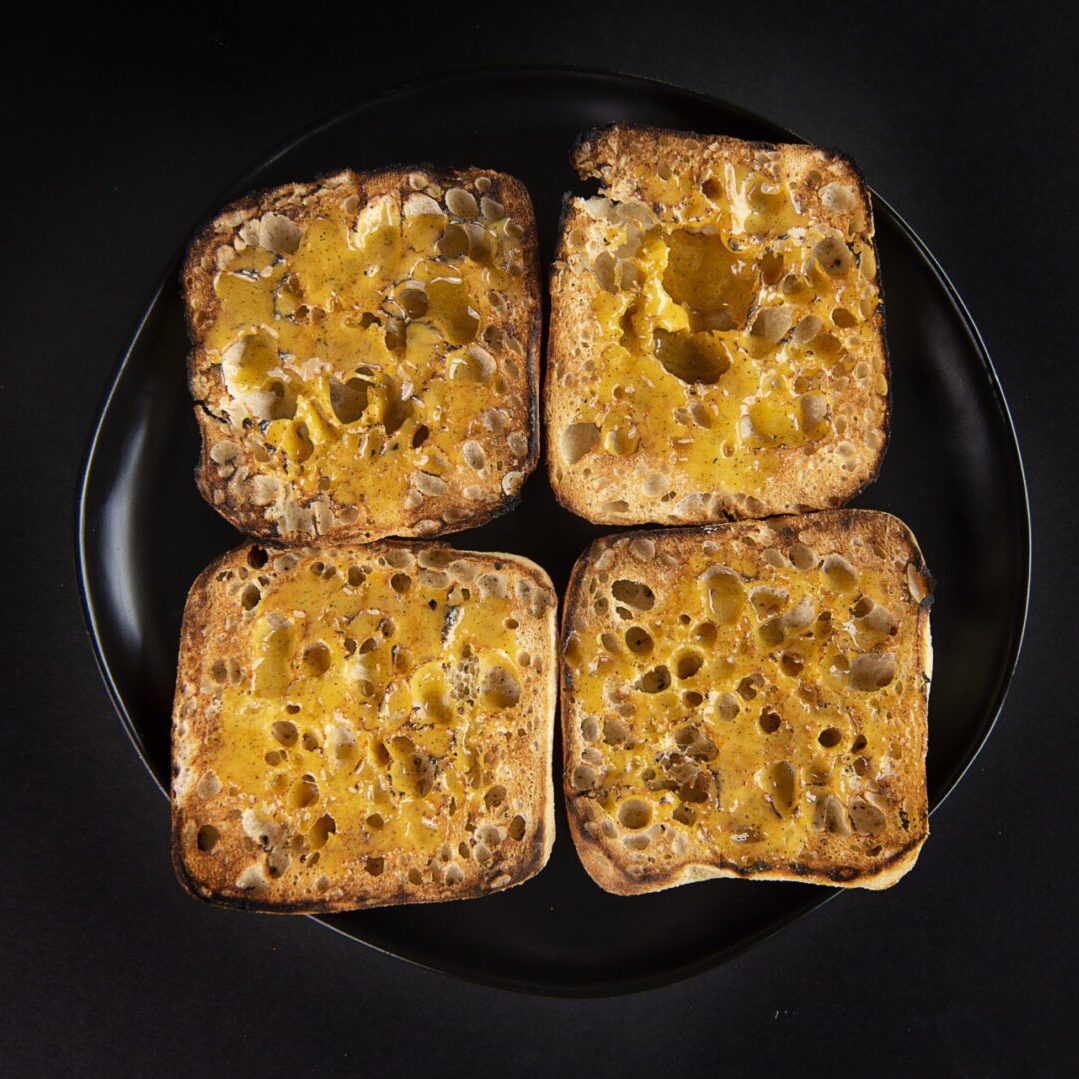 Four pieces of toast with cheese on them.
