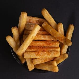 A bowl of fries with ketchup on top.