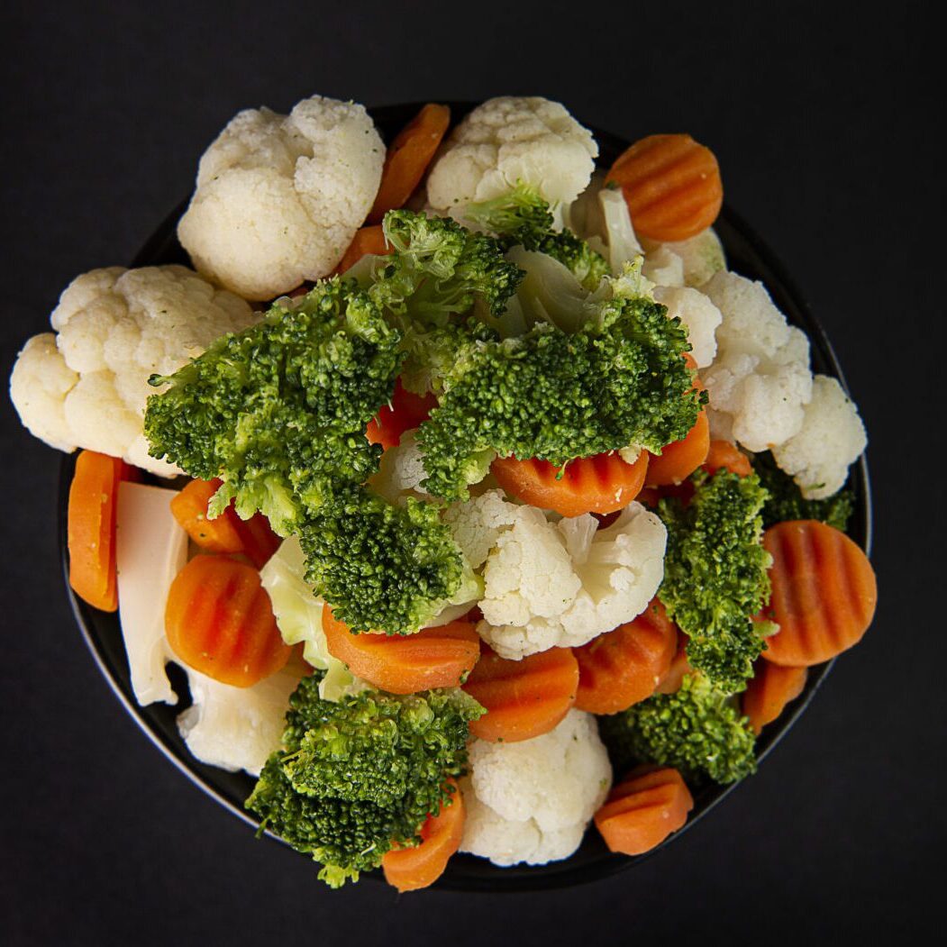 A bowl of broccoli, cauliflower and carrots on a table.