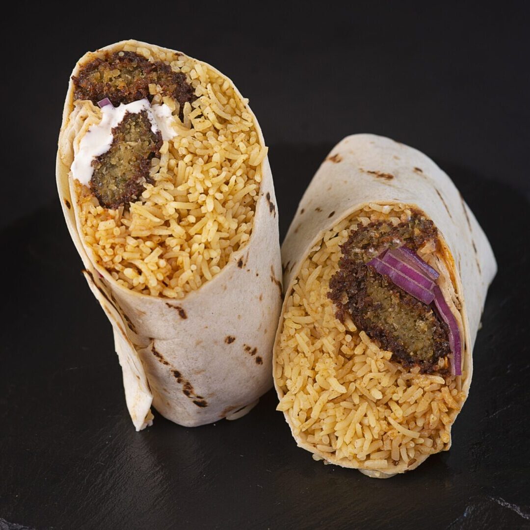 A burrito with rice and meat on top of it.