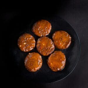 A black plate with six round cakes on it.