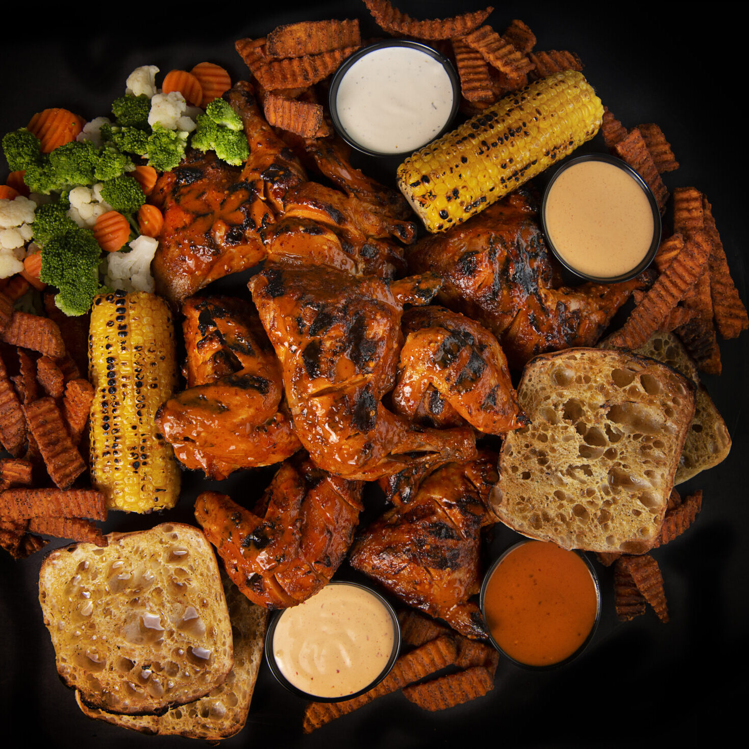 A plate of food with grilled chicken, corn and carrots.