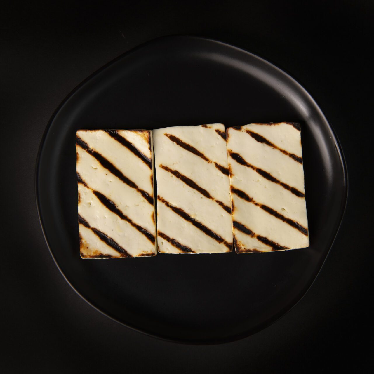 Three pieces of food on a black plate.